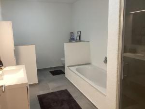 a white bathroom with a tub and a toilet at Schöne FeWo im Illertal in Oberopfingen
