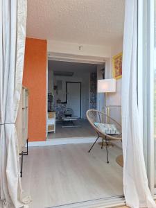 sala de estar con silla y pared de color naranja en Mimilou Eleuthera 300 m centre naturiste, en Cap d'Agde