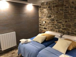 two beds in a room with a stone wall at Casa FOR HABITACIONES in Labuerda
