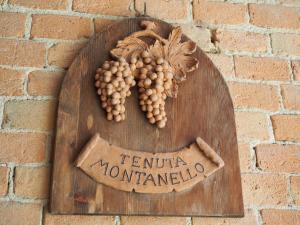 a sign on a brick wall with a bunch of grapes at Tenuta Montanello B&B in Castiglione Falletto