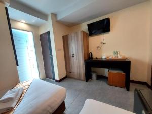 a bedroom with a bed and a desk and a television at Rustic Comfort Zone, Pattaya in Pattaya Central