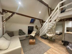 a living room with a couch and a loft bed at Petit duplex cosy coup de coeur, dans ferme de charme du 18 è siècle au milieu des champs in Bossut-Gottechain