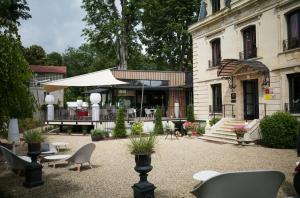 a patio with chairs and tables and a building at Domaine Le Verbois in Chantilly