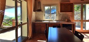 a kitchen with a table and some windows and a sink at Villa Giardino Aloe - Rifugio nella Natura Siciliana, Lontano dal Caos di Taormina in Castelmola