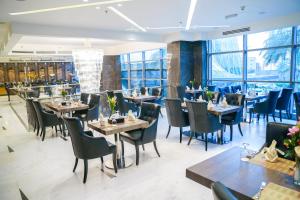 a restaurant with tables and chairs and windows at AlHamra Hotel Kuwait in Kuwait