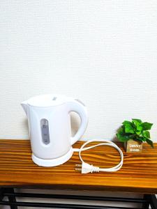 a white tea kettle sitting on a wooden table at Hotel Plum in Dazaifu