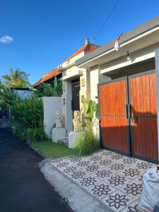 a house with a wooden gate and a driveway at Kubu In Dhana Guest House in Klungkung