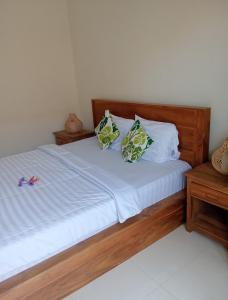 a bed with white sheets and two pillows at Kubu In Dhana Guest House in Klungkung