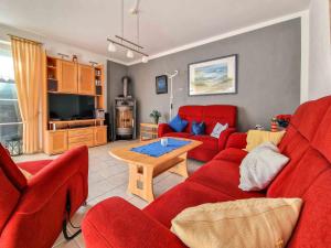 a living room with red couches and a table at Friedels Wohlfühloase in Greetsiel