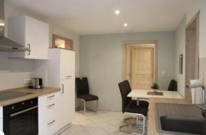 a kitchen with white cabinets and a table and chairs at Ferienwohnung Solitüde Strandnah in Flensburg