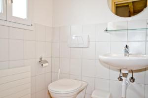 a white bathroom with a toilet and a sink at Delightful 4star Chalet Kiwi Apt in Grindelwald