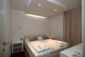 um quarto com uma cama com lençóis brancos e uma luz em Villa Paulina em Brela