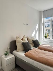 a bedroom with a bed with pillows and a window at Modernes Apartment am Marienplatz, Schwerin in Schwerin