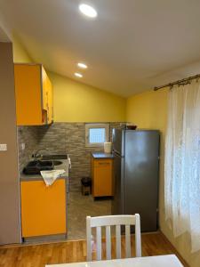 eine Küche mit gelben Wänden und einem Kühlschrank aus Edelstahl in der Unterkunft Prestige 3 in Podgorica