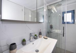 a white bathroom with a sink and a shower at Blue Balcony Boutique Beachfront Suite with Private Parking in Chania Town +59 photos