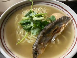 a bowl of soup with a fish and greens at おれっちのひみつきち3 in Shimada