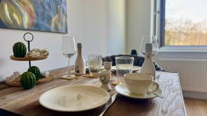 a wooden table with plates and wine glasses on it at Heaven Homes - Traumhafter Ausblick am Wald in Bad Driburg
