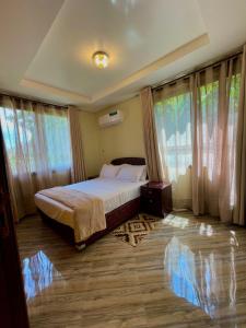a bedroom with a bed and two large windows at Bliss House in Dar es Salaam