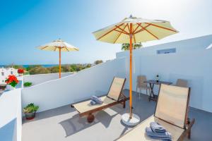a patio with two chairs and an umbrella on a roof at SantoriniNY in Perissa