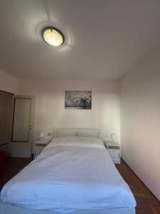 a bedroom with a large white bed and two tables at La finestra sul trenino in Tirano