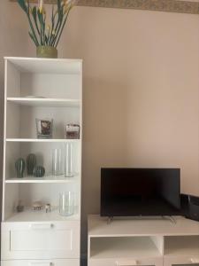 a white book shelf with a flat screen tv at La finestra sul trenino in Tirano