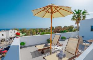 a patio with an umbrella and chairs on a roof at SantoriniNY in Perissa