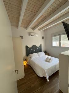 1 dormitorio con 1 cama blanca grande y cabecero de madera en Villa de la luz, en Tarifa