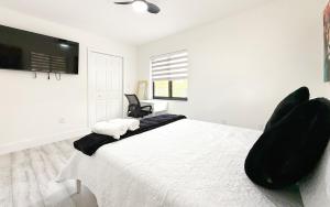 a white bedroom with a large bed with black chairs at Modern Oasis near Brickell & Marlins 2 Bedroom Free parking in Miami