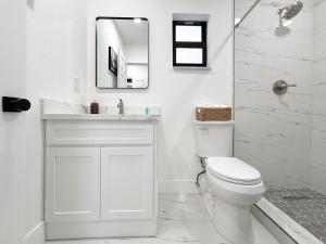 a white bathroom with a toilet and a mirror at Modern Oasis near Brickell & Marlins 2 Bedroom Free parking in Miami +23 photos