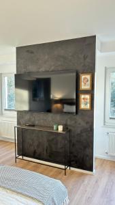 a living room with a black wall with a television at Heaven Homes - Traumhafter Ausblick am Wald in Bad Driburg