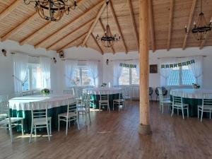 a room with white tables and chairs and chandeliers at Complex Turistic Padurea Mare in Bălţăteşti