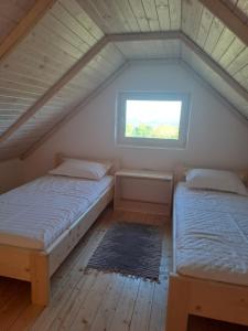 two beds in a attic room with a window at Complex Turistic Padurea Mare in Bălţăteşti