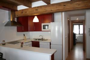 a kitchen with red cabinets and a white refrigerator at Apartamentos Panticosa in Panticosa
