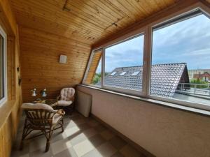 une pièce avec un balcon avec une chaise et des fenêtres dans l'établissement Ruhiges Stadtdomizil - Wohnkomfort in der Vier-Tore-Stadt, à Neubrandenbourg