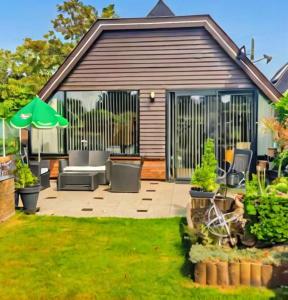 a patio with chairs and an umbrella in a yard at Spacious Nature Escape, house for 6 near Amsterdam & Sea in Opmeer