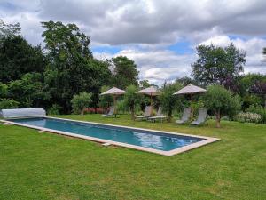 a swimming pool in a yard with chairs and umbrellas at Villa Paignon Studio in Montbron