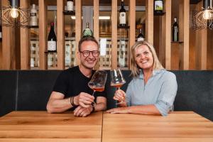 un uomo e una donna seduti a un tavolo con bicchieri da vino di MONS suites wine passion a Tannheim