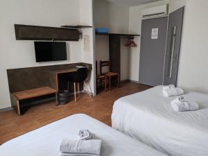 a hotel room with two beds and a flat screen tv at Hotel Marjolaine in Roullet