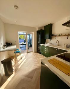 a kitchen with green cabinets and a wooden floor at Waterside House - Luxury Home near Alton Towers & Trentham - Free Parking & Garden in Stoke on Trent