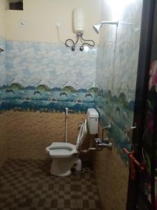 a bathroom with a toilet with a painting on the wall at Ishwar Place Rooms and Cafe Gokarna in Gokarna