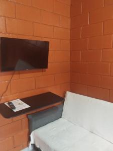 een kamer met een muur met een tv en een stoel bij Pousada da Vila Araçariguama-SP in Araçariguama