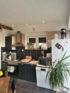 a kitchen with a white refrigerator and a table at LE GAI LO GITE in Villers-Pol