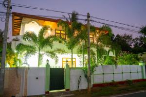a house with a white fence and palm trees at Kanapathiy Rest House in Trincomalee