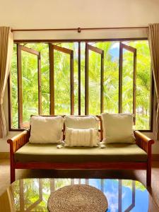 ein Sofa in einem Zimmer mit einem großen Fenster in der Unterkunft Villa Mona-Beachfront Sunset Peaceful Garden Villa in Nathon Bay
