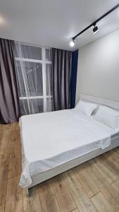 a white bed in a room with a window at 1 комнатные апартаменты in Semey +4 photos