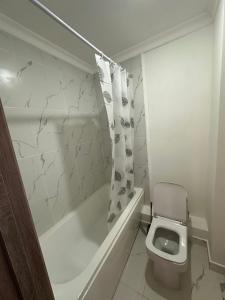 a white bathroom with a toilet and a bath tub at Harmony Inn in Almaty +34 photos