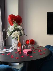 a table with roses and a bottle of champagne and glasses at La Suite Prestige - Jacuzzi et cinema - Cergy-Village in Cergy