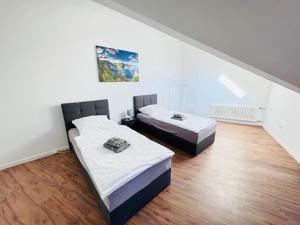 2 Betten in einem Zimmer mit weißen Wänden und Holzböden in der Unterkunft 23-schöner Wohnen, großes Apartment für 5-6 Personen in super Lage in Duisburg
