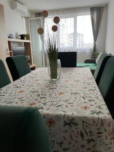 a dining room table with a vase on top of it at Green Apartman in Paraćin