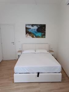 a white bedroom with a white bed and a painting at Casa Vacanze Martina in Piombino